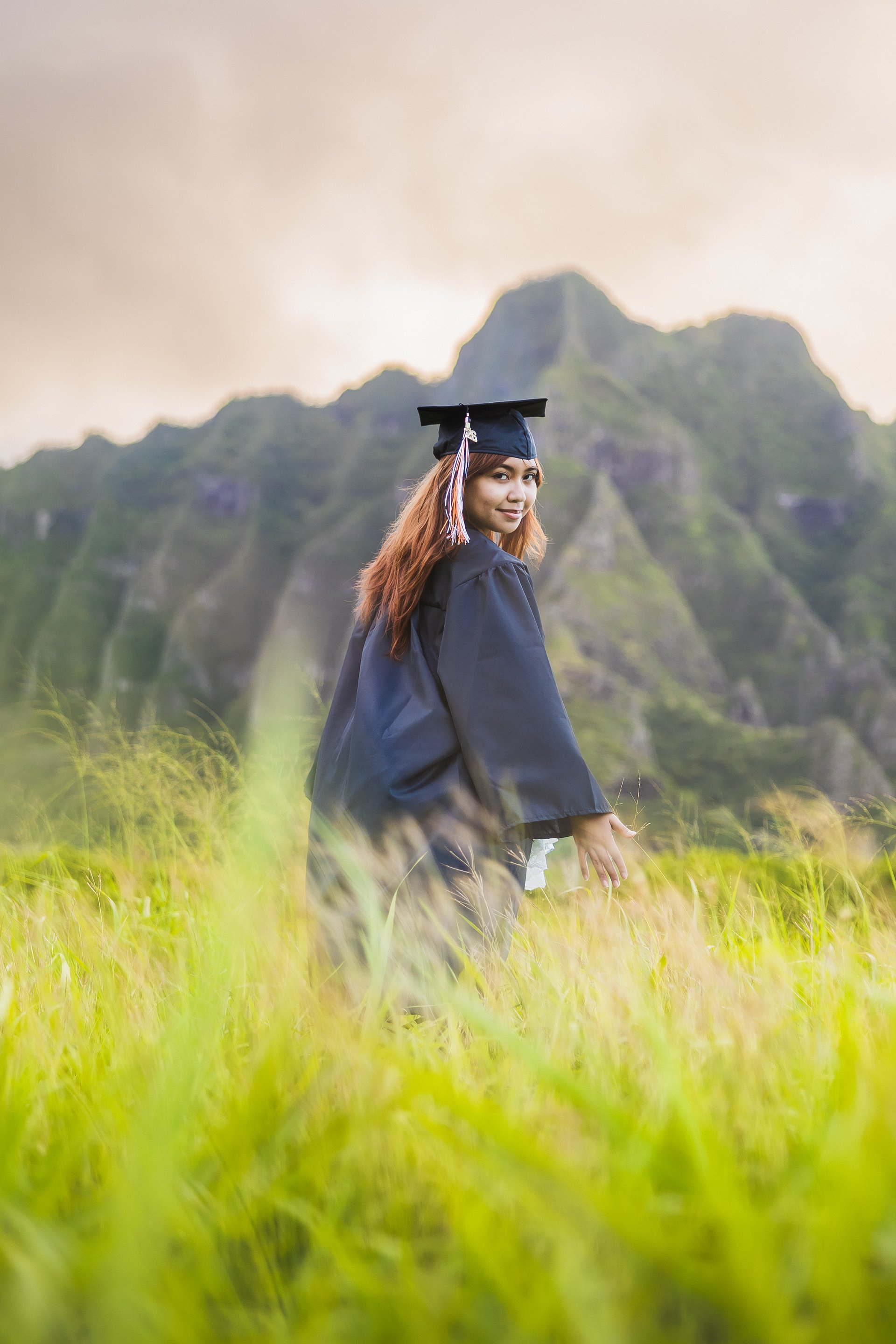 Graduate celebrating in cap and gown at Kualoa Ranch on Oahu Hawaii