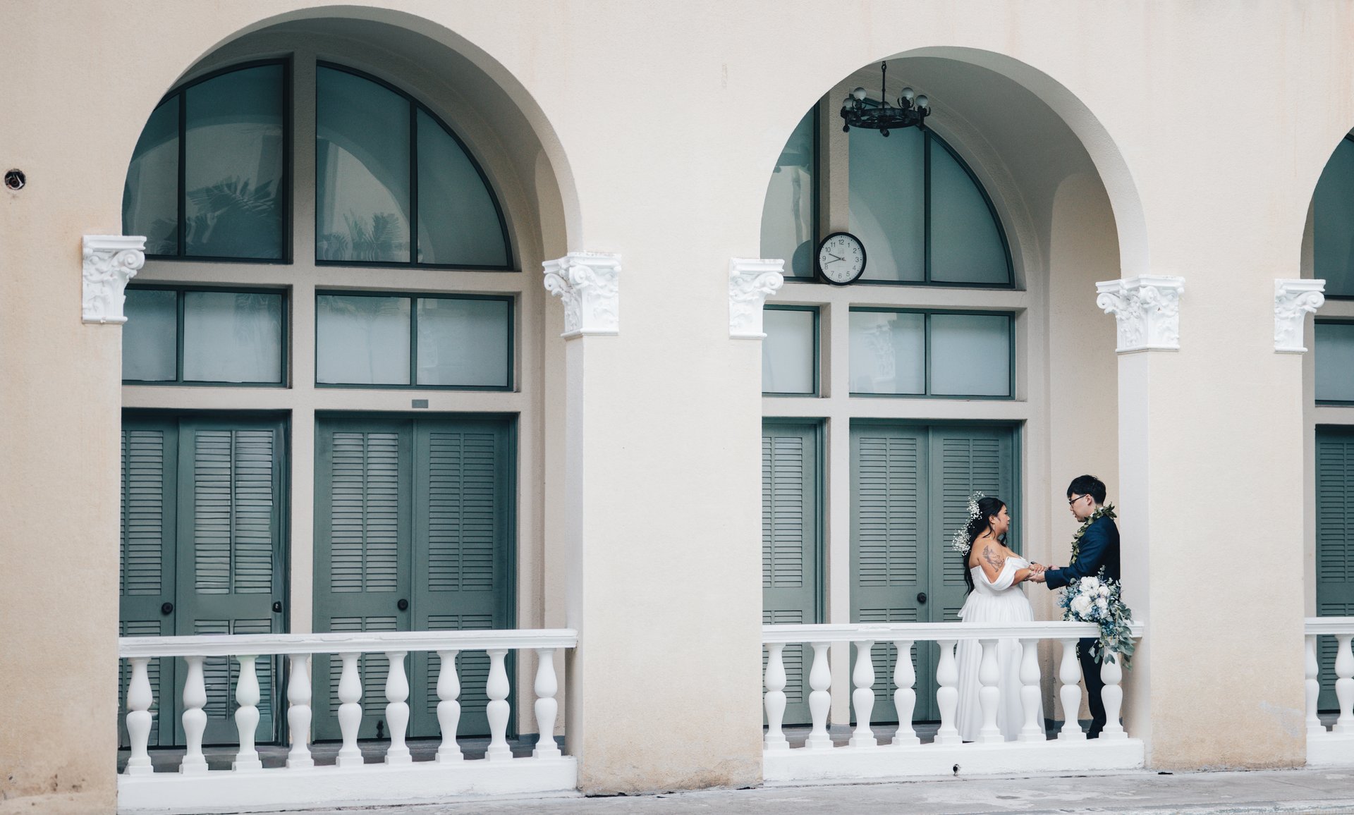 Bride and groom embrace on balcony at historic Honolulu wedding venue
