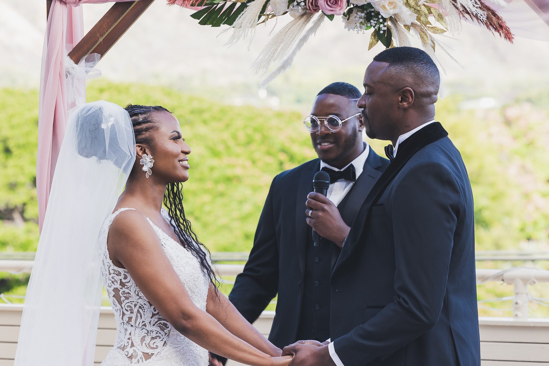 Bride and groom exchange vows under floral arch at outdoor Hawaii wedding ceremony